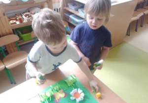 Chłopcy przyklejają kwiatki na łące