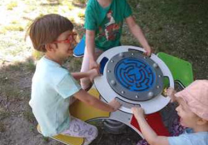 Dziewczynki podczas zabaw swobodnych w ogrodzie przedszkolnym korzystają z dostępnych sprzętów ogrodowych