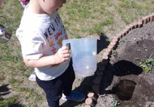 Chłopiec trzyma w dłoniach konewkę z wodą