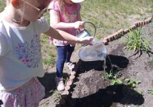 Zosia i Tosia podlewają rośliny zasadzone w ogrodzie przedszkolnym