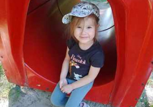 Dziewczynka siedzi w tunelu ogrodowym, który znajduje się w naszym ogrodzie przedszkolnym