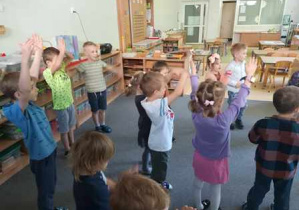 Dzieci tańczą na dywanie podczas zabawy ruchowej do piosenki pt. "Spotkanie na polanie"