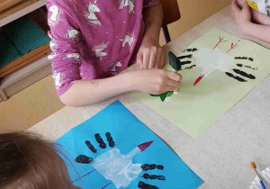 Dzieci odbijają bociany z dłoni pomalowanych farbą