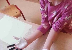 Dziewczynka pokazuje dłonie pomalowane na biało czarno