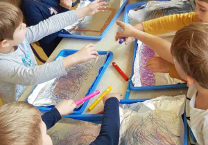 Dzieci malują mazakami folię aluminiową, tworząc tło do pracy plastycznej
