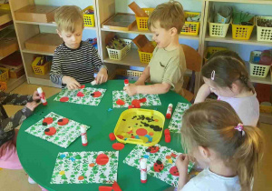 Dzieci przyklejają biedronki na karton