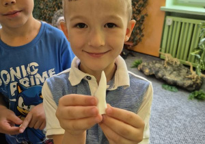 Chłopiec pozuje do zdjęcia z zębem dinozaura