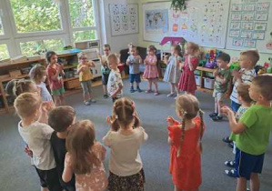 Dzieci tańczą w kręgu na dywanie