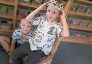 Natanek siedzi na urodzinowym tronie i poprawia sobie koronę