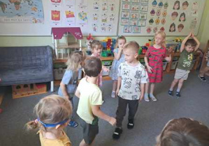 Dzieci tańczą na dywanie podczas zabawy ruchowej do piosenki pt. "Spotkanie na polanie"