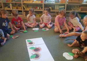 Dzieci układają papierowe jabłuszka, na których spisano wspomnienia z wycieczki