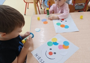 Dzieci przyklejają kolorowe koła, tworząc pajacyka