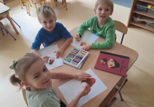 Dzieci siedzą przy stoliku i rysują portret M. Montessori