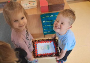 Liwia i Franio trzymają portret M. Montessori