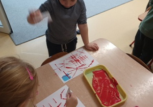 Dzieci stemplują linie za pomocą czerwonej farby