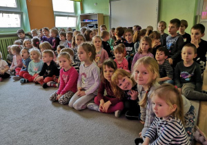 Dzieci siedzą na dywanie czekając na przedstawienie