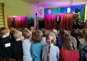 Dzieci oglądają przedstawienie, na scenie stoi aktor