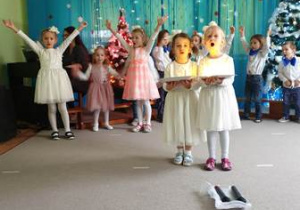 Dzieci śpiewają kolędę, na środku Ala i Zuzia trzymają rekwizyty - opłatek oraz świecące lampki