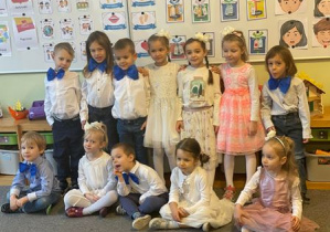 Dzieci w odświętnych strojach pozują do zdjęcia grupowego przed przedstawieniem jasełkowym