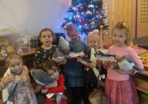 Dziewczynki z grupy oglądają prezenty, które dostały od Świętego Mikołaja - maskotki delfinków i czekoladki.