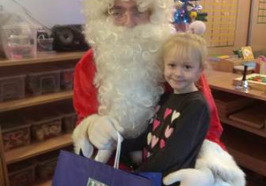 Dziewczynka przytula się do Świętego Mikołaja.