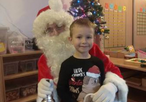 Chłopiec otrzymuje prezent od Mikołaja. Święty Mikołaj dzwoni dzwonkiem.