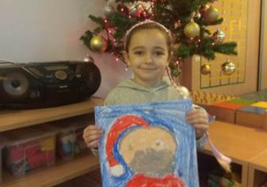 Dziewczynka pokazuje narysowany wizerunek Świętego Mikołaja.