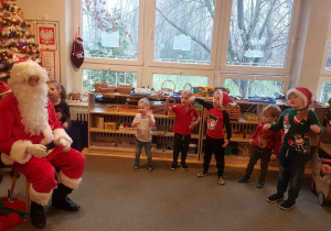 Mikołaj słucha piosenki, a dzieci pokazują ją gestem.