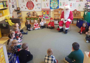 Dzieci siedzą w kręgu i rozmawiają z Mikołajem.