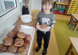 Chłopiec degustuje pączki.
