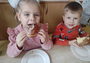 Dzieci jedzą pączki.