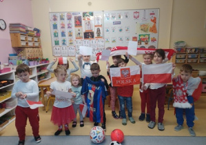 Grupa dzieci prezentuje przyniesione flagi i przybory do kibicowania