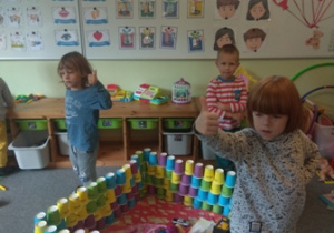 Dzieci prezentują skonstruowaną budowlę z kubków papierowych