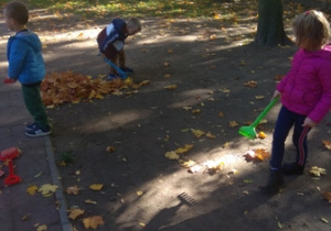 Dzieci grabią liście w ogrodzie