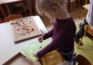 Dziewczynka z wykorzystaniem magnesu szuka przedmiotów ukrytych w pojemniku z ryżem