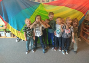 Chłopcy stoją do pamiątkowego zdjęcia na tle kolorowej chusty animacyjnej.