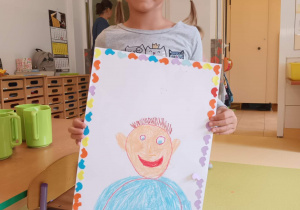 Dziwczynka pokazuje portet chłopaka, którego narysowała.