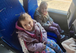 Dwie dziewczynki siedzą w autokarze i oczekują na wyjazd do "Baśniowej Kawiarenki"
