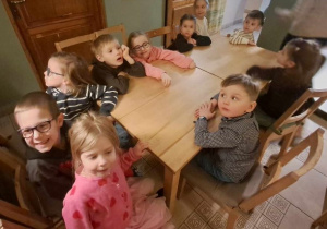 Dzieci siedzą przy stole i oczekują na rozpoczęcie przedstawienia