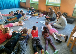 Dzieci słuchają bajki terapeutycznej, czytanej przez prowadzącą
