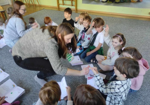 Dzieci siedzą w kręgu podczas warsztatów, odpowiadają na pytania