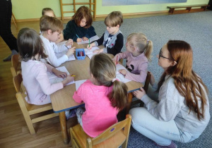 Dzieci siedzą przy stoliku i rysują w książeczkach