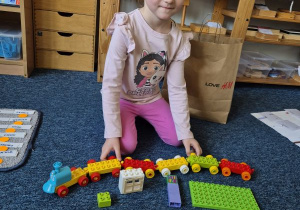 Dziewczynka pozuje do zdjęcia z klockami Lego