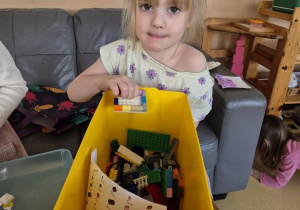 Dziewczynka pozuje do zdjęcia z klockami Lego