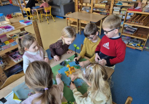Dzieci budują z klocków Lego siedząc przy stoliku