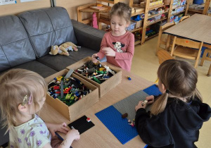 Dzieci budują z klocków Lego siedząc przy stoliku