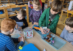 Dzieci budują z klocków Lego siedząc przy stoliku