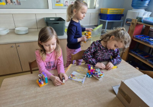 Dziewczynki budują z klocków Lego siedząc przy stoliku