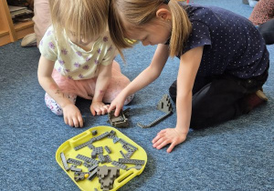 Dziewczynki budują budowlę z klocków Lego w jednym kolorze