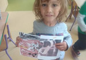Chłopiec prezentuje wykonaną pracę plastyczną. Są to dorysowane brakujące fragmenty zdjęcia psa.